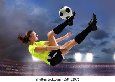 Female soccer player performing bicycle kick with large stadium in background
