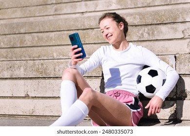 female soccer player resting using mobile phone - Powered by Shutterstock