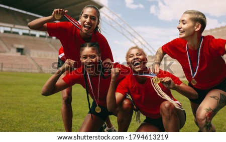 Female soccer players cheering together after the game league. Football team with medals screaming together after winning the competition.