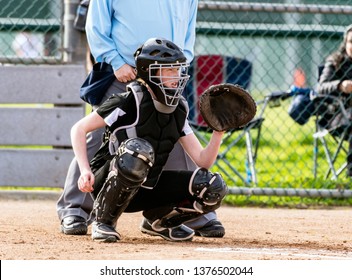 Female softball catcher in full protective gear ready to catch the first pitch. - Powered by Shutterstock