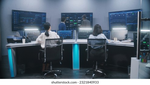 Female software engineer sits at computer with displayed blockchain network and surveillance maps. Technical support specialists work in monitoring room. Multiple big screens on the wall. Dolly shot. - Powered by Shutterstock