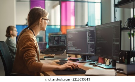 Female Software Engineer Writing Code on Desktop Computer with Multiple Screens Setup in Stylish Coworking Office Space. Professional Caucasian Woman Working on SaaS Platform For Innovative Startup.