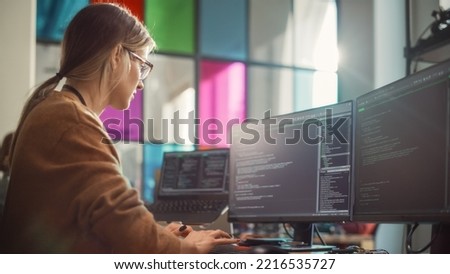 Female Software Engineer Writing Lines of Code on Professional Multiple Display PC Setup In Stylish Office. Caucasian Woman Fixing Bugs and Creating New Features For Innovative Digital Service.