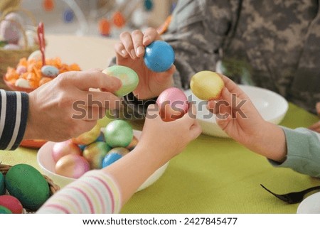 Female soldier with her family breaking Easter eggs at dinner, closeup