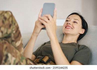 Female Soldier Lies On A Couch And Holds A Mobile Phone In Her Hands