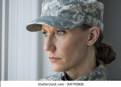 A female soldier looking out a window, blank stare