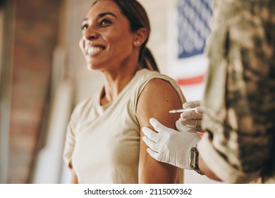 Female Soldier Receiving A Dose Of The Covid-19 Vaccine In Her Arm. United States Servicewoman Smiling Happily While Getting Inoculated Against Coronavirus Disease In The Military Hospital.