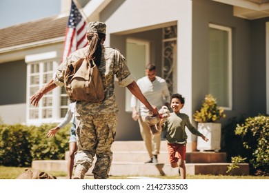Female soldier reuniting with her family after serving in the army. American servicewoman receiving a warm welcome from her husband and kids. Military woman returning home from deployment.