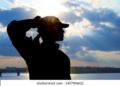 Female soldier in uniform saluting outdoors. Military service