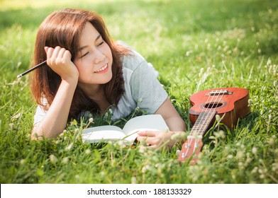 Female Song Writer. Thinking With Notebook And Little Guitar On Her Side