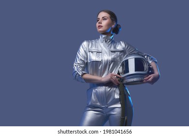 Female space explorer in spacesuit holding helmet