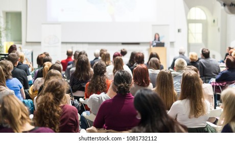 Female speaker giving presentation in lecture hall at university workshop. Audience in conference hall. Rear view of unrecognized participant in audience. Scientific conference event. - Shutterstock ID 1081732112