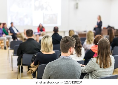 Female speaker giving presentation in lecture hall at university workshop. Audience in conference hall. Rear view of unrecognized participant in audience. Scientific conference event. - Shutterstock ID 1273120234