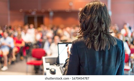 Muttersprachlerin, die einen Vortrag über Unternehmenskonferenzen hält. Unerkennbare Menschen im Publikum im Konferenzsaal. Veranstaltung "Unternehmen und Unternehmertum".