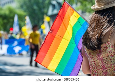 A female spectator is holding the gay rainbow flag at the 2015 Gay Pride Parade in Montreal. - Powered by Shutterstock