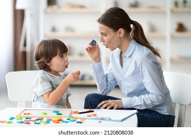 Female speech therapist curing child's problems and impediments. Little boy learning letter O with private English language tutor during lesson at office - Shutterstock ID 2120808038