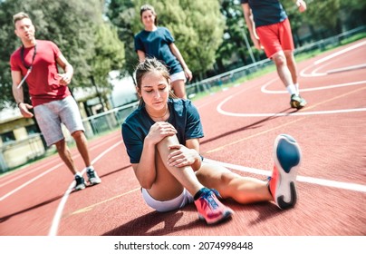 Female sportler getting injured at athletic workout training - Male coach taking care on sport pupil after physical accident - Team concept with young sporty people facing bad mishaps casualty - Powered by Shutterstock