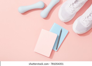 Female Sports Flat Lay, Dumbbells, Notepad, Sneakers On Pink Background, New Year Fitness Resolutions