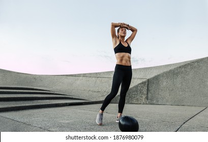 Female in sportswear feeling exhausted after intense training. Woman taking a break after workout outdoors with a medicine ball on ground. - Powered by Shutterstock