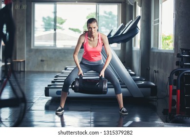 Female In Sportswear Lifting Heavy Bag While Exercising In Gym