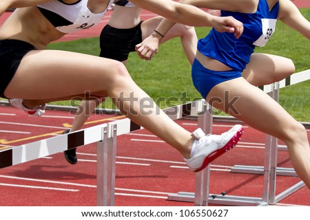 Female sprinter leaping over hurdles