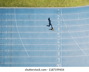 Female sprinter running on athletic track nearing the finish line. Top view of a sprinter running on race track in a stadium. - Shutterstock ID 1187199454