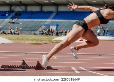 female sprinter start running from starting blocks running on stadium track, summer athletics championship - Powered by Shutterstock