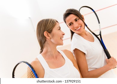 Female squash players at the court holding rackets