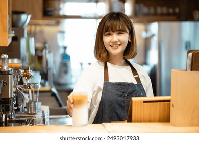 The female staff in the coffee shop works with a smile, professionally brewing coffee, pouring over coffee with hot water and filter paper in cafe. - Powered by Shutterstock