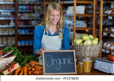 Female staff holding organic sign board in supermarket - Powered by Shutterstock