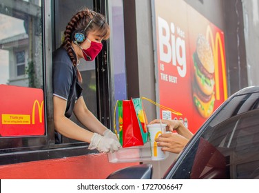 Female staff at McDonald's deliver food to customers through the door of the car at the pick up point in Bangkok, Thailand, 29/04/2020.
