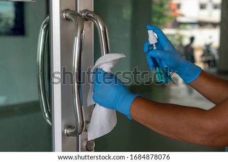 Female Staff using wet wipe and alcohol sanitizer spray to clean the door handle. Antiseptic,disinfection ,cleanliness and heathcare, anti virus concept. Anti Corona virus (COVID-19). Selective focus.
