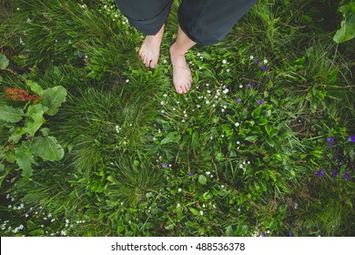 Female standing barefoot on green grass and flowers