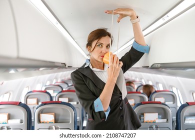 Female Stewardess Demonstrating How To Use Oxygen Mask In Plane