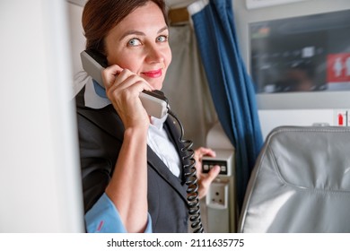 Female Stewardess Talking On Telephone In Airplane