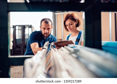 Female Stock Clerk Checking Inventory With A Help Of Warehouse Worker