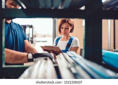 Female Stock Clerk Checking Inventory With A Help Of Warehouse Worker