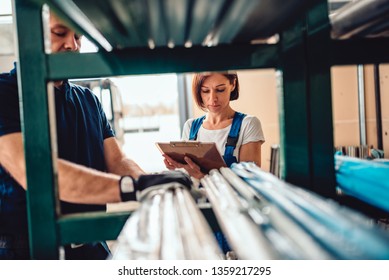 Female Stock Clerk Controlling Inventory With A Help Of Warehouse Worker