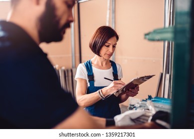 Female Stock Clerk Controlling Inventory With A Help Of Warehouse Worker