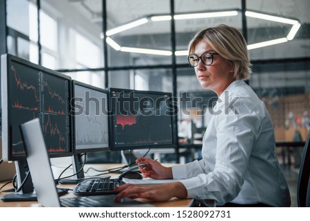 Female stockbroker in formal clothes works in the office with financial market.