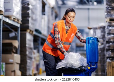 A female storage worker putting plastic bags into recycle bin.
