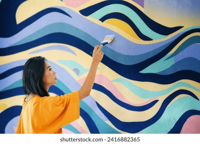 Female street artist painting bright colorful graffiti on wall Modern art, urban concept. Full length portrait - Powered by Shutterstock