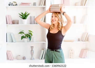 Female student balancing books on top of her head. Beautiful blonde girl keeps a stack of books on her head. The concept of education, courses, examinations, homework, list of books to read.