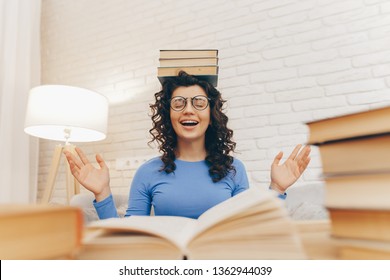 Female student balancing books on top of her head. Beautiful brunette girl keeps a stack of books on her head. The concept of education, courses, examinations, homework, list of books to read