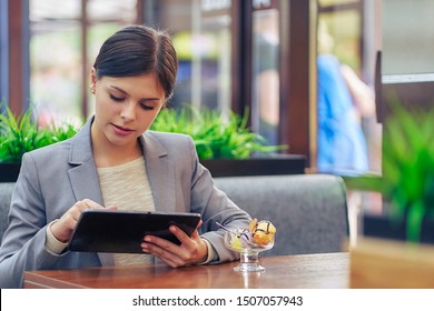 female student in a cafe with a tablet and ice cream - Shutterstock ID 1507057943