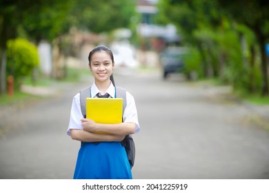 Female Student Carrying Backpack And Book In The Outdoor.Back To School Malaysian Child.Secondary Student Portrait In Malaysia.Education In Asia.Chinese Girl Wearing Uniform.Smiling Thai Kid.