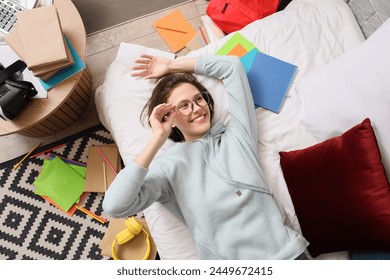 Female student with copybooks lying in bedroom, top view - Powered by Shutterstock