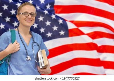 Female Student Doctor With Stethoscope And Books In Hand On The US Flag Background. Medical Education Concept. Medical Learning In USA