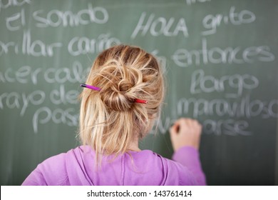 Female Student During Spanish Class In Front Of A Blackboard With Pen In Hair