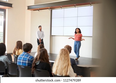 Female Student Giving Presentation To High School Class In Front Of Screen